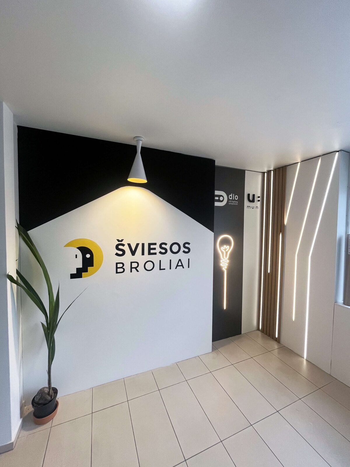 Šviesos brolių patalpos iš vidaus — logotipo siena ir LED apšvietimo ekspozicija